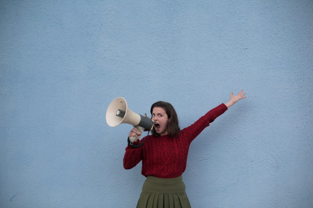 a girl shouts using a horn