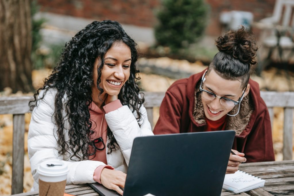 a girl and a boy ar sitting in front of a laptop